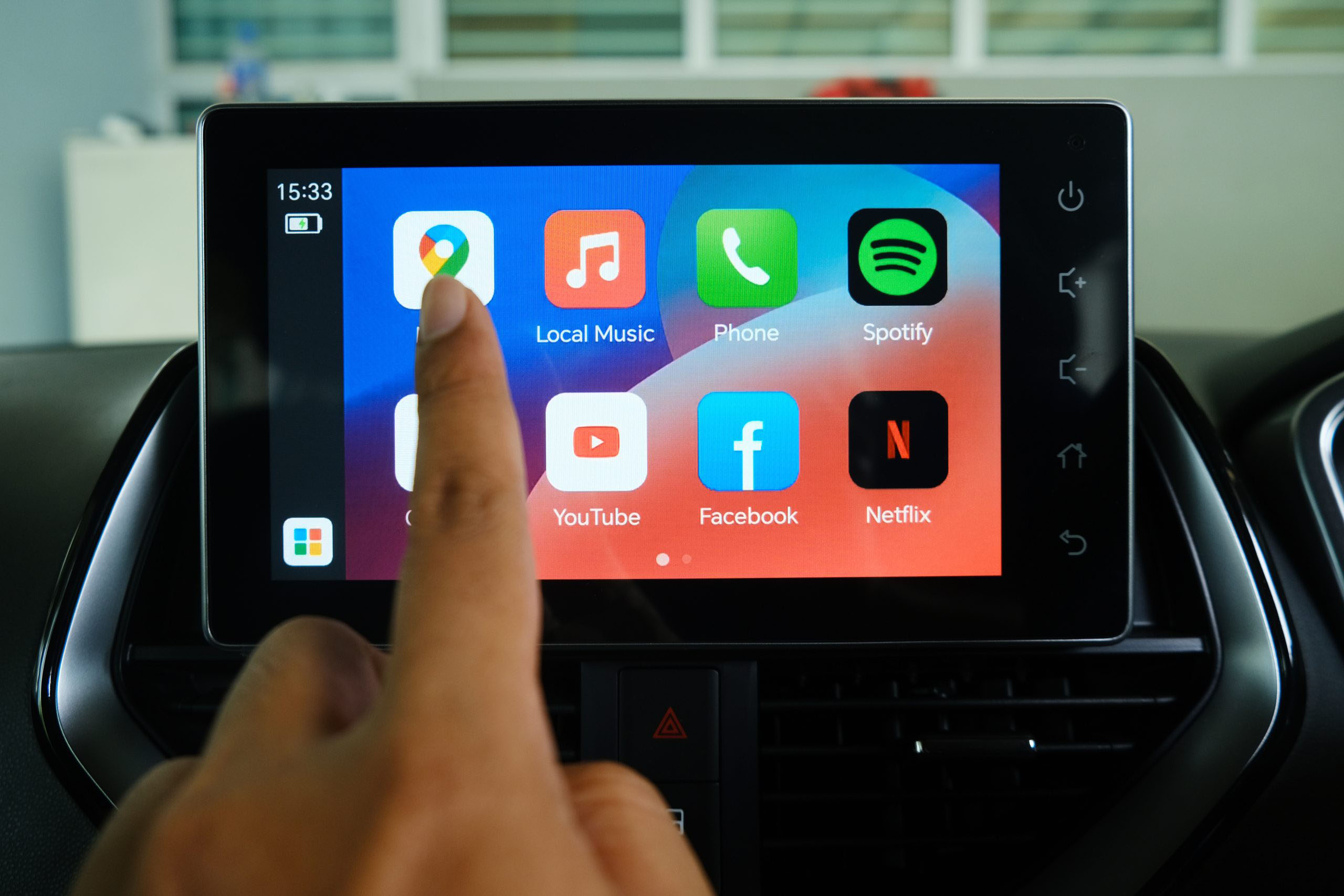 A finger tapping an app on a touchscreen device inside a car.