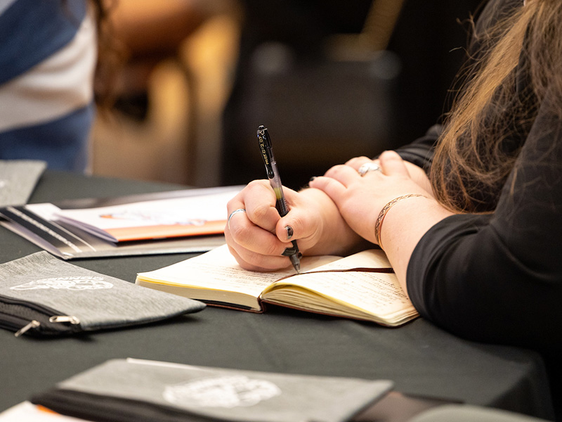 A woman writing in a notebook at a table.