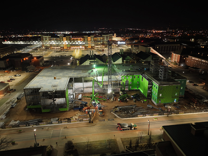 Front of the building as workers pour concrete in early morning