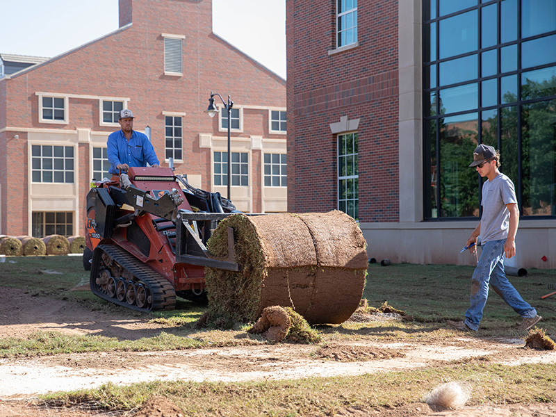 Rolling out sod outside new building
