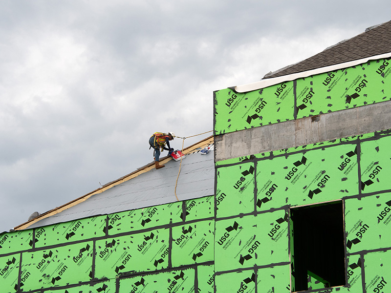 Worker installing shingles on roof