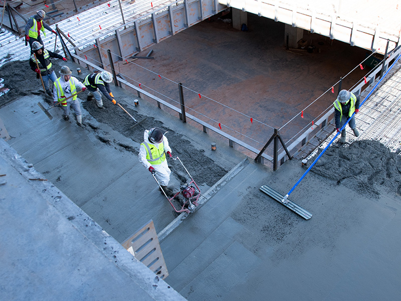 Workers leveling concrete on construction site